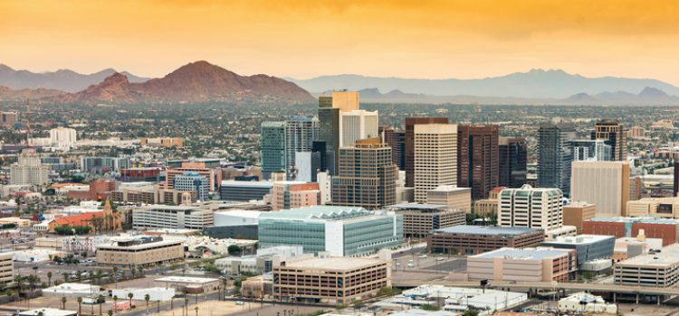 The Phoenix, Arizona skyline at dusk with an orange sky and mountains in the background