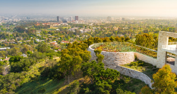 a view of the getty center and the surrounding trees and green space, with los angeles in the background