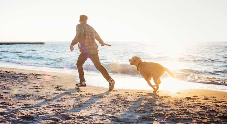 a man and his dog run in the surf at Fort Funston Beach in San Francisco