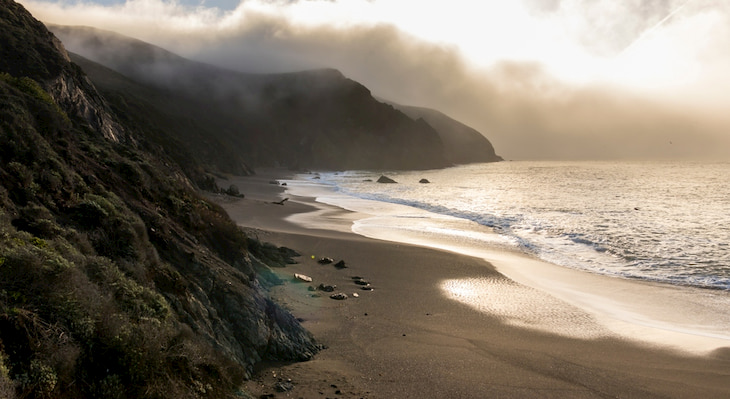 the sun rises over Black Sands Beach In Sausalito, California