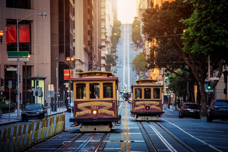 vintage cable cars moving down a narrow san francisco street